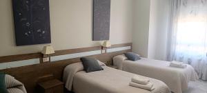 a room with two beds and a window at Pension Casa Curro in Palas de Rei
