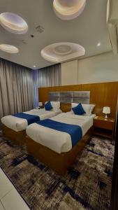two beds in a hotel room with blue pillows at حياه الأصيل للشقق الفندقية in Jeddah