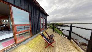 a chair sitting on the deck of a house at Brenna - Ocean View Apartment in Hellissandur