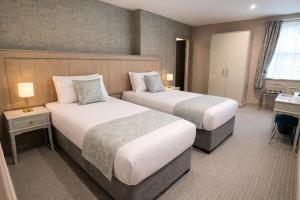 a hotel room with two beds and a desk at Hotel Rue in Omagh