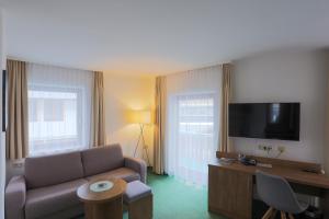 a living room with a couch and a flat screen tv at Hotel Dachstein in Filzmoos