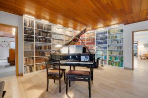 a library with a piano in a room with bookshelves at Stilvoller Bauhaus Bungalow mit Sauna in Lüneburger Heide für 8 Gäste in Wohlendorf