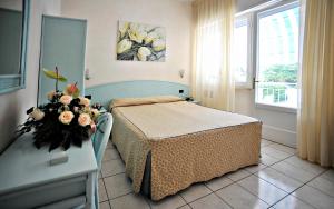 a bedroom with a bed and a table with flowers on it at Hotel Riviera Blu in Tirrenia