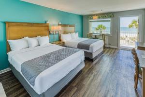 two beds in a hotel room with blue walls at The Islander Inn in Ocean Isle Beach