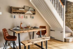 a dining room with a table and chairs and stairs at Old Stable Cottage in Kingham