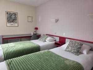 a hotel room with two beds and a green blanket at Hotel Saint Odilon in Cluny +37 photos