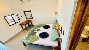 a small bedroom with a bed with blue pillows at Surf Wave Hotel in Arugam Bay