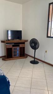 a room with a television and a fan in the corner at Refugio Paraiso in Arraial do Cabo