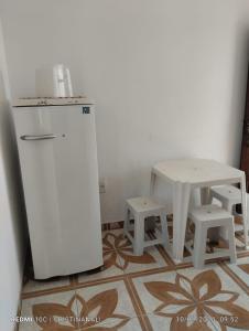 a kitchen with a table and a refrigerator and stool at Kitinet in Marataizes