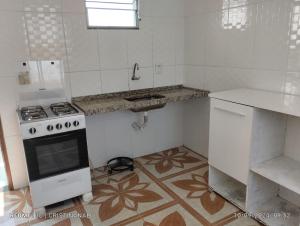 a white kitchen with a stove and a sink at Kitinet in Marataizes