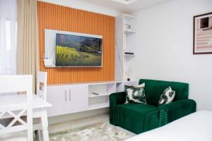 a living room with a green couch and a tv at Shanny's Cozy Studio in Eldoret