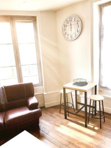 a living room with a couch and a clock on the wall at Le Repos Poitevin Studio Atypique in Vivonne