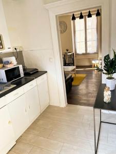a kitchen with white cabinets and a living room at Le Repos Poitevin Studio Atypique in Vivonne