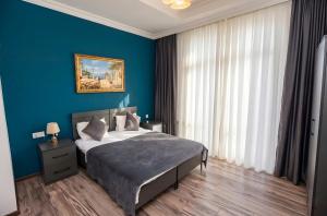 a bedroom with a bed with a blue wall at Green Garden Hotel in Baku