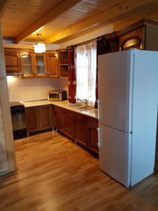a kitchen with a white refrigerator and wooden cabinets at Casa de la Lac in Sighetu Marmaţiei