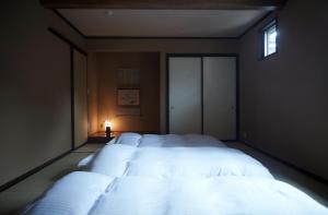 a bedroom with a large bed with white sheets at 一棟宿 倉持 in Kusatsu