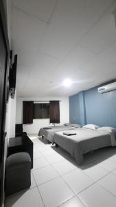 a room with three beds and a chair in it at Hotel confort in Guayaquil