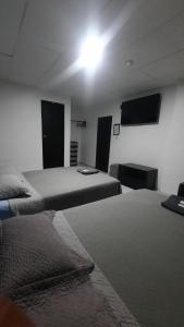 a room with two beds and a flat screen tv at Hotel confort in Guayaquil
