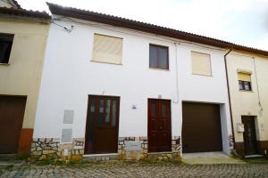 a white building with two doors and a garage at Casa Ti Madalena in Arganil
