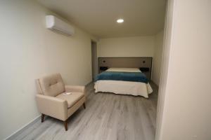 a small bedroom with a bed and a chair at Casa Ti Madalena in Arganil
