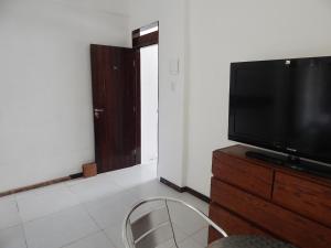 a living room with a television on a wooden dresser at Pousada Beira Litoral in João Pessoa +9 photos