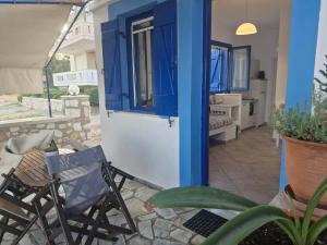 a house with a blue door and chairs and a patio at Thalias apartments in Kómi +35 photos