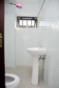 a white bathroom with a toilet and a sink at Shanny's Cozy Studio in Eldoret +27 photos