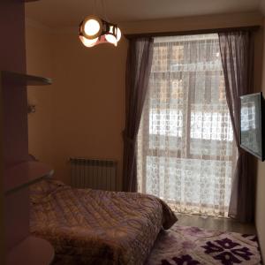 ein Schlafzimmer mit einem Bett und einem großen Fenster in der Unterkunft Deer Villa in Zaghkadsor