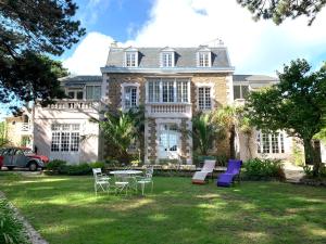 a large house with chairs and tables in the yard at Maison d'hôtes Villa Meinga in Saint-Coulomb