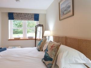 a bedroom with a bed with white sheets and a window at Steading Cottage - Ukc5957 in Port Appin
