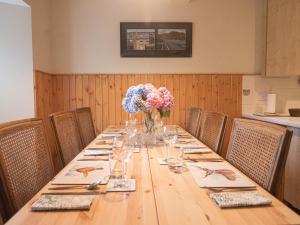 a long wooden table with a vase of flowers on it at Steading Cottage - Ukc5957 in Port Appin +4 photos