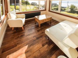 a living room with a couch and a table and windows at Hilbre in Strachur