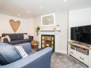 a living room with a blue couch and a tv at Pencefn Cottage in Llanddeiniolen