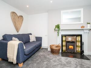 a living room with a blue couch and a fireplace at Pencefn Cottage in Llanddeiniolen