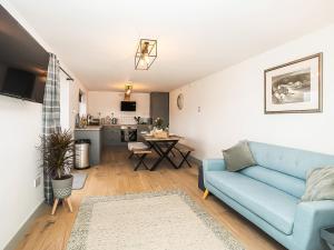 a living room with a blue couch and a kitchen at Pencefn Cottage in Llanddeiniolen