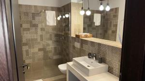 a bathroom with a sink and a toilet and a mirror at Vendi Grand Square Residence in Sibiu