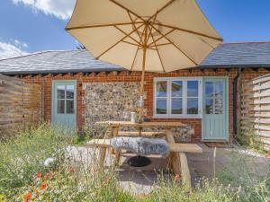 a picnic table with an umbrella in front of a house at Swallow - Uk50155 in Faversham