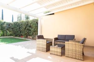 eine Terrasse mit Korbstühlen und einer Pergola in der Unterkunft Green Lodge in Marco Simone