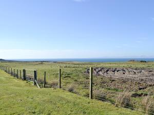 a fence in a field with the ocean in the background at Belloch Cottage in Glenbarr