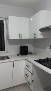 a white kitchen with white cabinets and a stove at Casa Nury in Santo Domingo