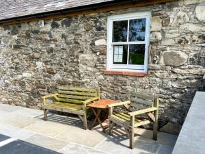 two chairs and a table in front of a stone building at Landberrick Farm Bothy 1 in Mochrum