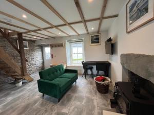 a living room with a green couch and a piano at Landberrick Farm Bothy 1 in Mochrum