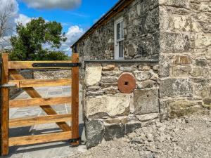 a stone building with a wooden gate and a window at Landberrick Farm Bothy 1 in Mochrum