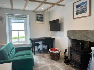a living room with a green couch and a fireplace at Landberrick Farm Bothy 1 in Mochrum