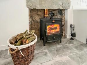 a stove in a room with a basket of logs at Landberrick Farm Bothy 1 in Mochrum +4 photos