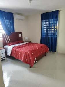 a bedroom with a red bed with blue curtains at Casa Nury in Santo Domingo