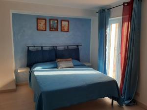 a blue bedroom with a bed and a window at Al Palmento in Galati Mamertino