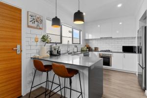 a kitchen with a counter and two stools in it at Steps to the Beach Cafes moderm stylish 3BR in Christies Beach