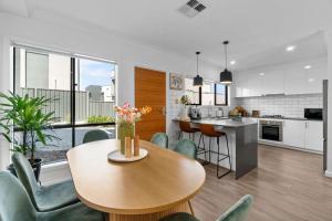 a kitchen and living room with a table and chairs at Steps to the Beach Cafes moderm stylish 3BR in Christies Beach