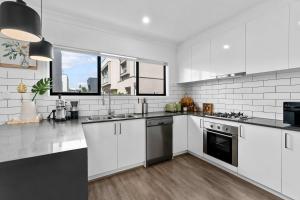 a white kitchen with white appliances and a window at Steps to the Beach Cafes moderm stylish 3BR in Christies Beach +28 photos
